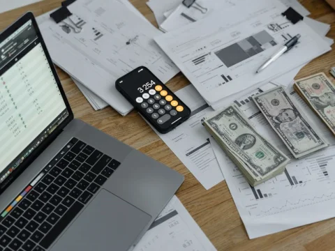 Calculator, cash, and financial documents on a desk